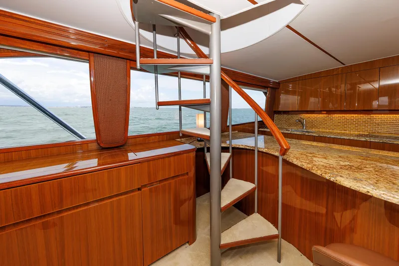 On Ice Yacht Photos Pics Luxurious interior of 2009 Viking 74 Enclosed Bridge yacht with spiral staircase and wooden finishes.