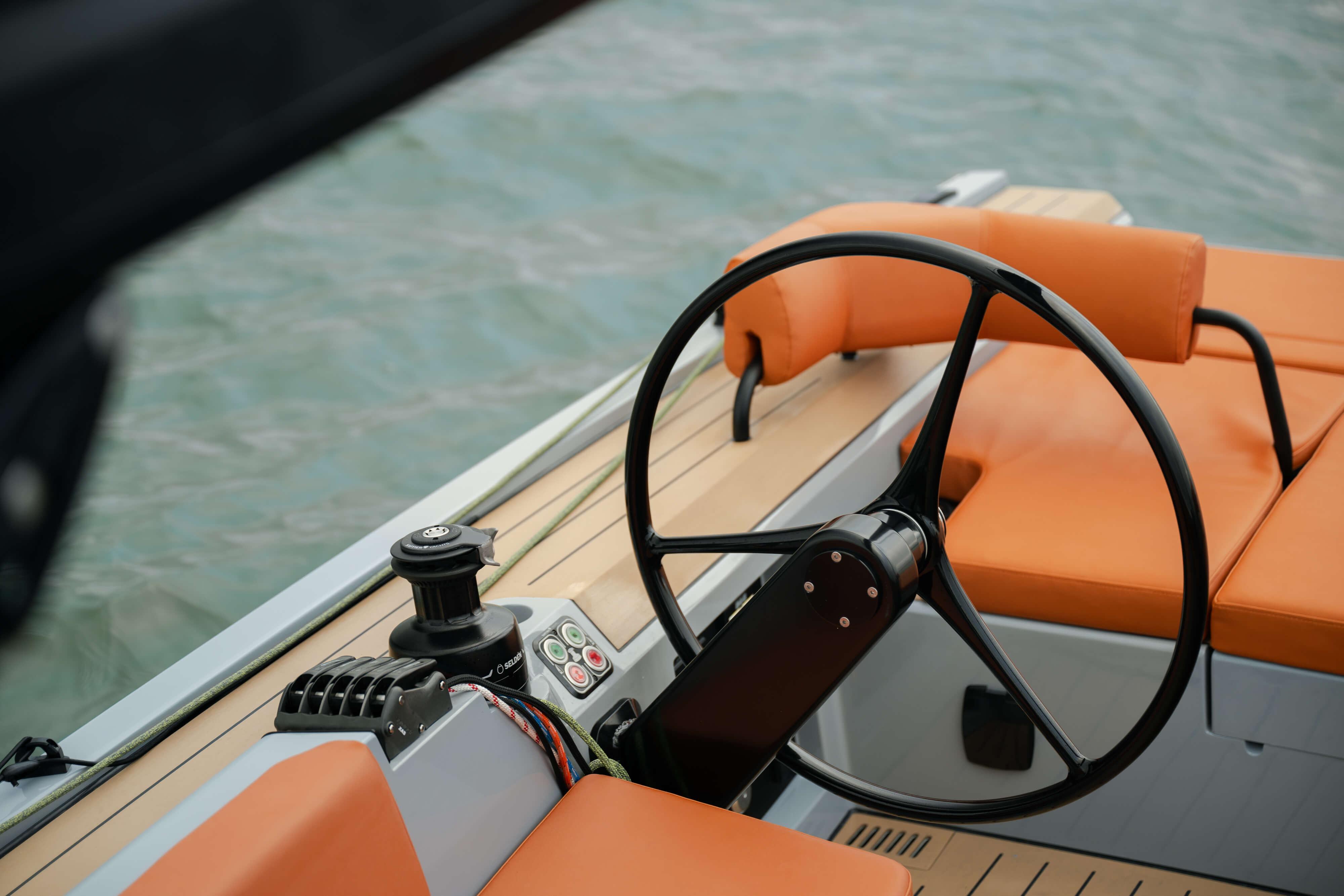 Steering wheel of 2026 Saffier SE 28 Leopard yacht with orange seating, on water.