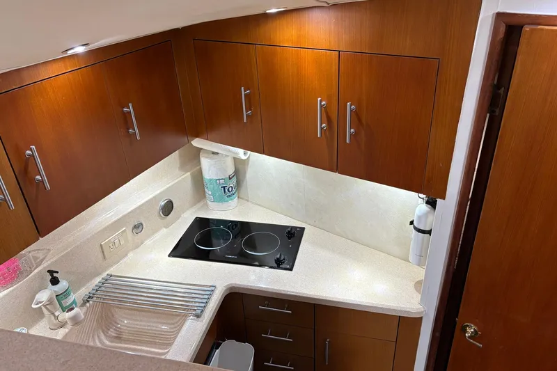 Andiamo Yacht Photos Pics Compact kitchen in 2001 Ocean 40 Express Bridge yacht with wooden cabinets and electric stove.