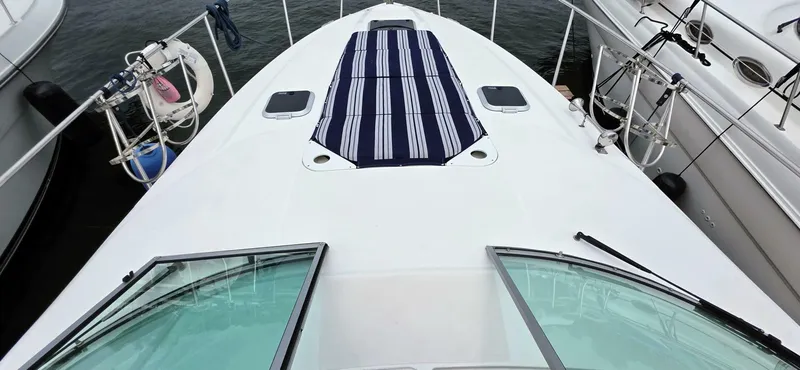  Yacht Photos Pics 2007 Rinker 350 Express boat deck with striped sun pad, docked beside other boats.