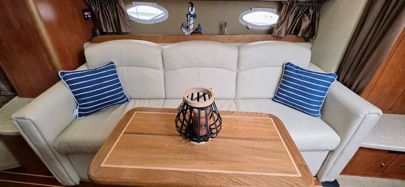 Yacht Photos Pics Interior of 2007 Rinker 350 Express with beige sofa, striped pillows, and wooden table.