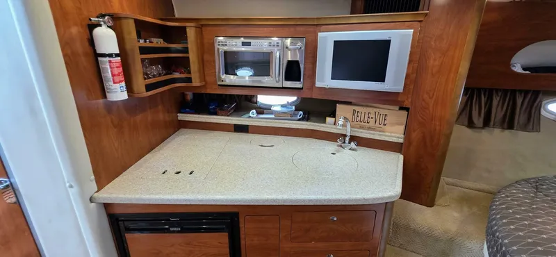  Yacht Photos Pics 2007 Rinker 350 Express yacht interior with kitchenette, microwave, TV, and wooden cabinetry.