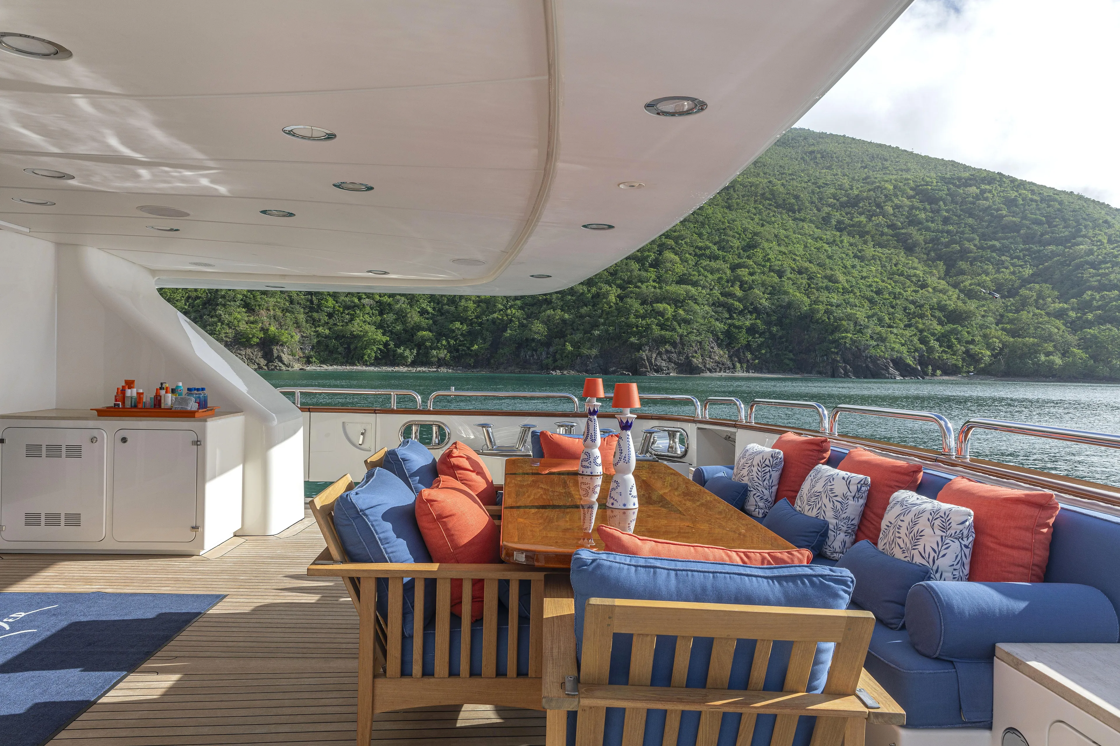 Sur La Mer Yacht Photos Pics Luxurious Benetti Vision 145 yacht deck with elegant seating, scenic ocean view, and lush green backdrop.