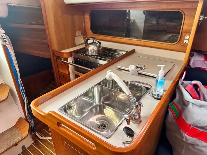 "legacy" Yacht Photos Pics 2006 J Boats J/109 yacht interior with compact kitchen, stainless steel sink, and wooden cabinetry.