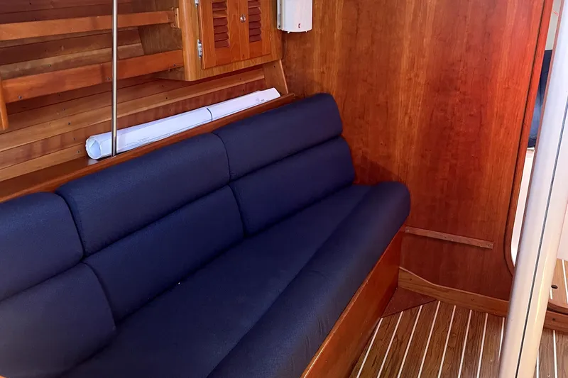 "legacy" Yacht Photos Pics Interior of 2006 J Boats J/109, featuring a blue cushioned bench and wooden paneling.