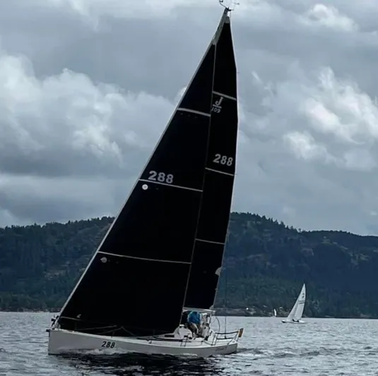 "legacy" Yacht Photos Pics Sailing yacht J/109 from 2006 on a cloudy day, with scenic hills in the background.