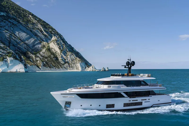  Yacht Photos Pics 2023 Custom Line Navetta 30 yacht cruising near a rocky coastline.