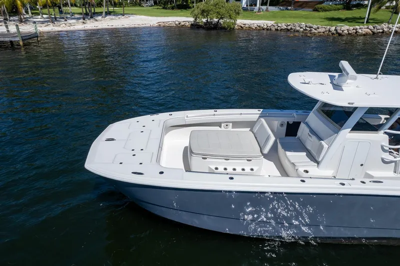  Yacht Photos Pics 2019 Invincible 37 Catamaran cruising near a sandy shoreline with lush greenery.