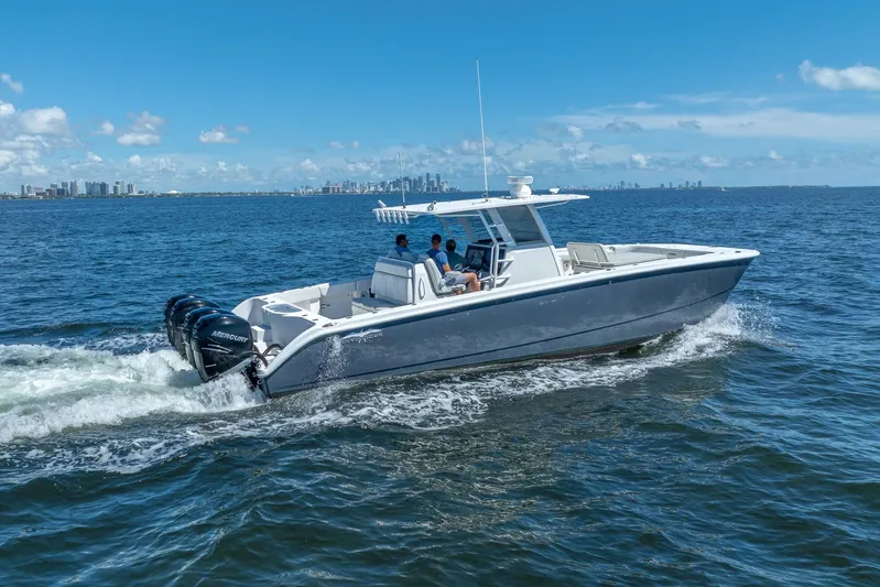  Yacht Photos Pics 2019 Invincible 37 Catamaran cruising on open water with city skyline in background.