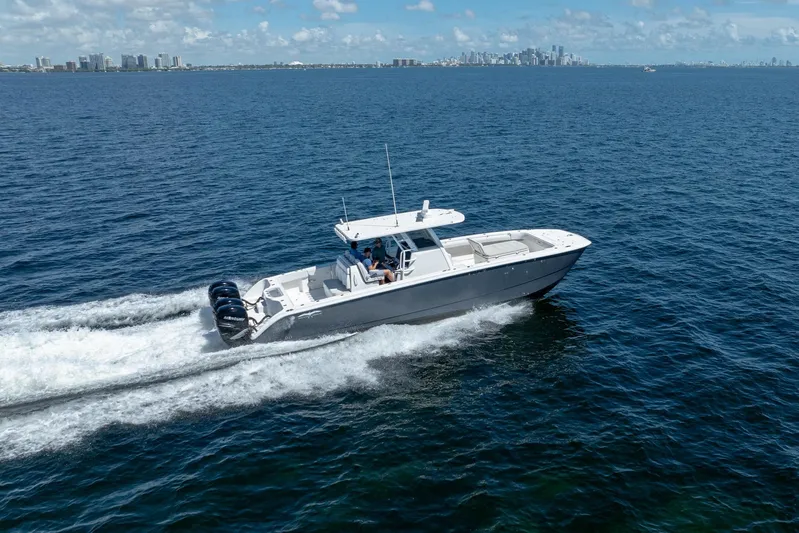  Yacht Photos Pics 2019 Invincible 37 Catamaran cruising on open water with city skyline in background.