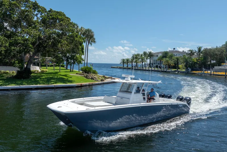  Yacht Photos Pics 2019 Invincible 37 Catamaran cruising near a scenic waterfront estate.