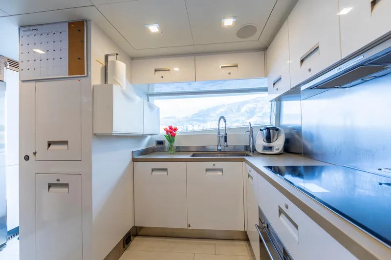 Centurion Yacht Photos Pics Modern yacht kitchen with sleek white cabinets, stainless steel appliances, and a scenic window view.