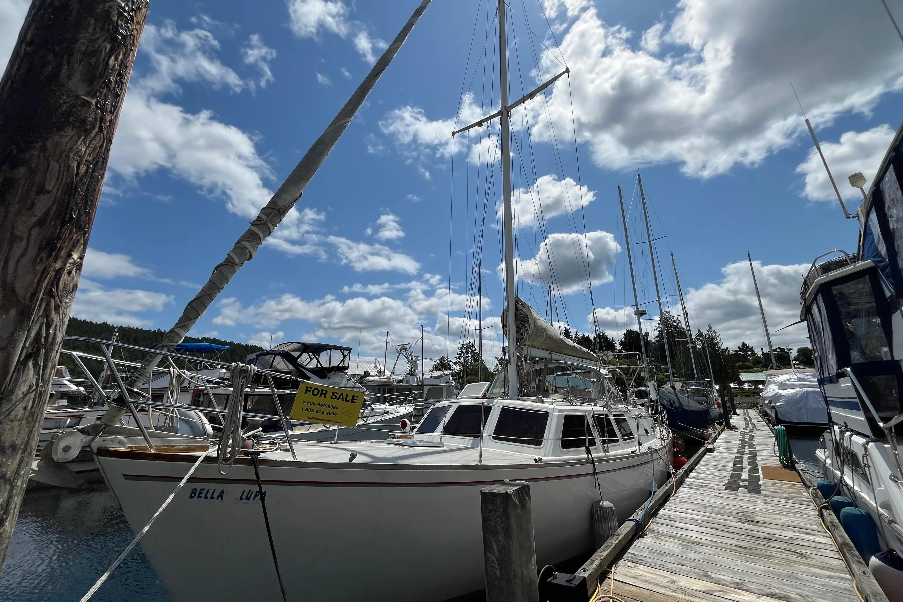1972 CAL 2-46 sailboat docked, "For Sale" sign, clear sky, marina setting.