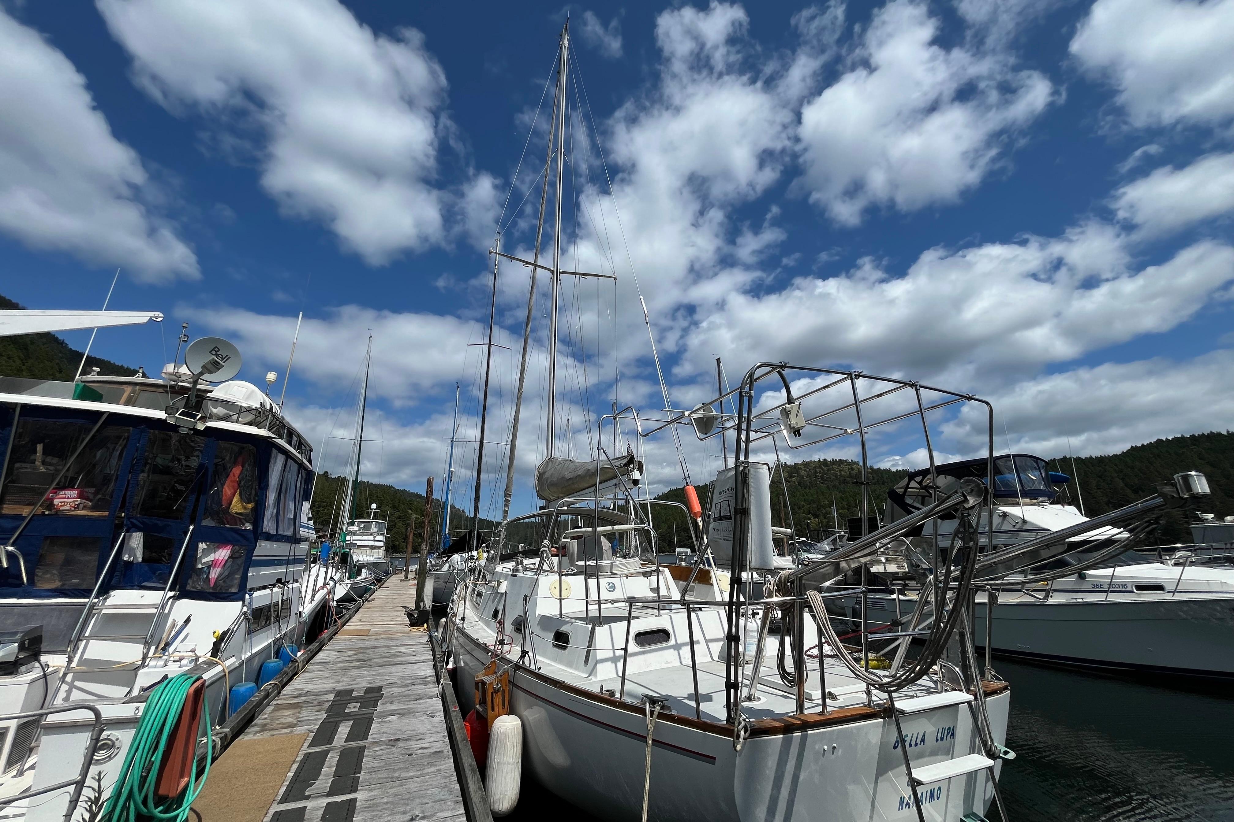 Sailboats docked at a marina under a partly cloudy sky, featuring a 1972 CAL 2-46 model.