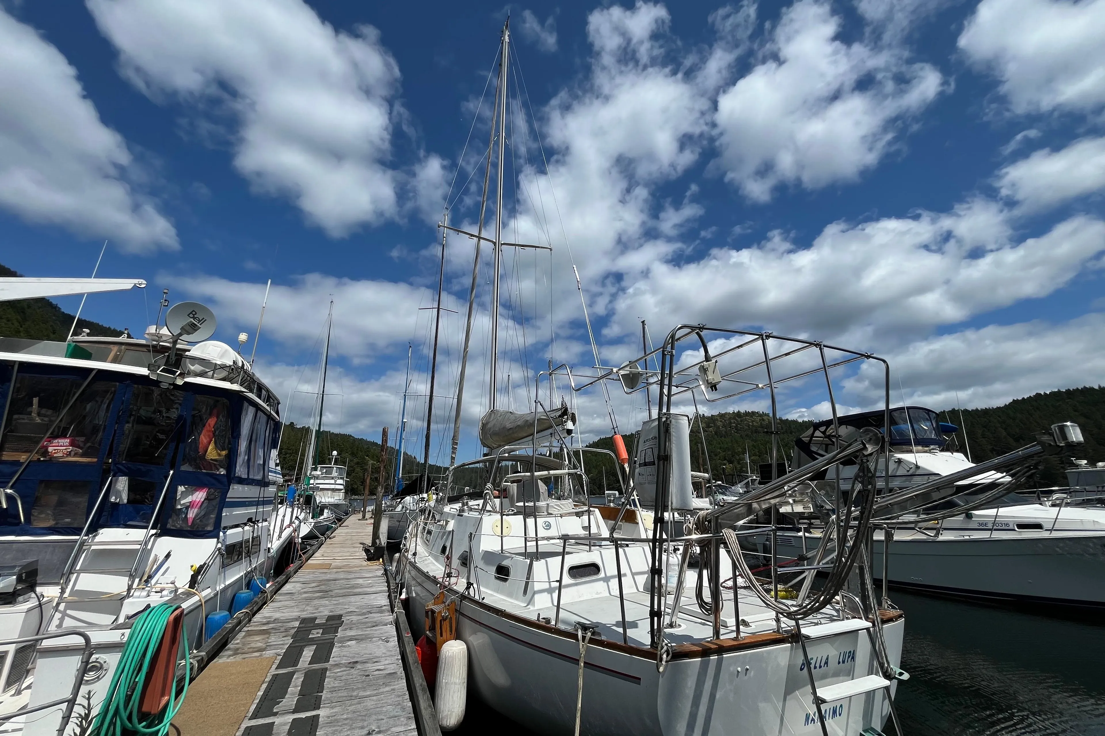 Sailboats docked at a marina under a partly cloudy sky, featuring a 1972 CAL 2-46 model.