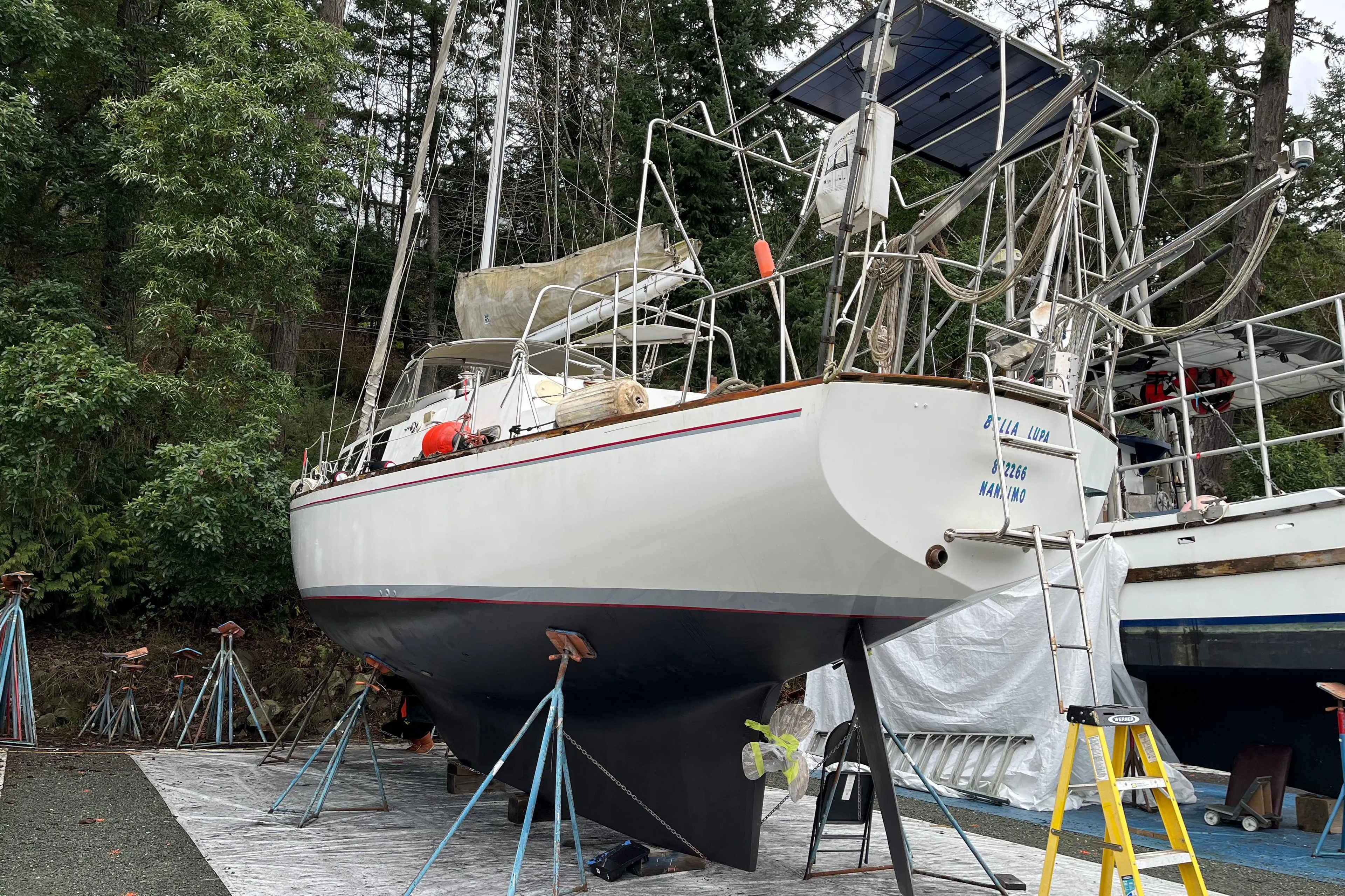 1972 CAL 2-46 sailboat on stands, surrounded by trees, ready for maintenance.