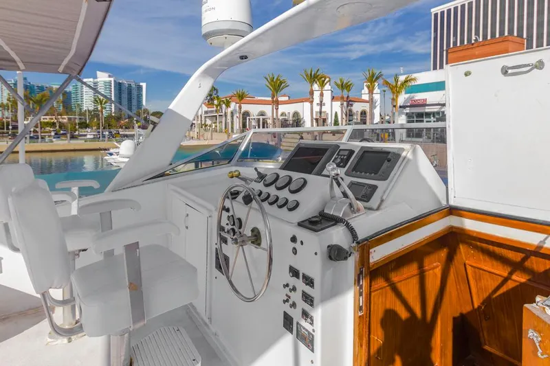  Yacht Photos Pics 1981 Hatteras Extended Deckhouse yacht helm with modern controls, docked in sunny marina.