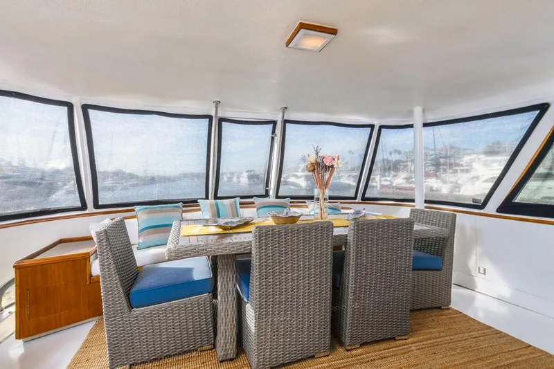  Yacht Photos Pics Spacious dining area on 1981 Hatteras Extended Deckhouse yacht with wicker chairs and panoramic windows.