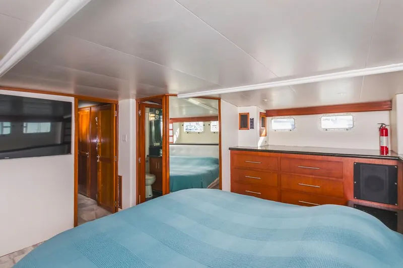  Yacht Photos Pics Interior of 1981 Hatteras Extended Deckhouse with wood cabinetry and blue bedding.