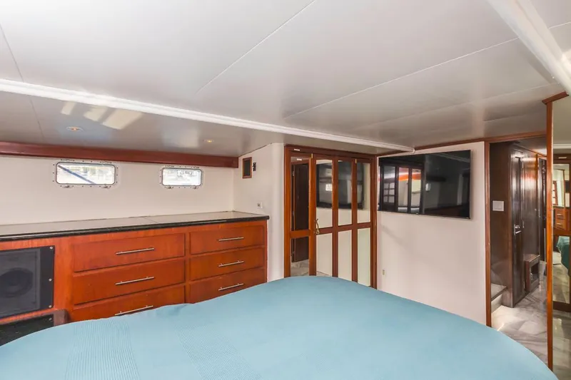  Yacht Photos Pics Luxurious 1981 Hatteras Extended Deckhouse bedroom with wood cabinetry and modern decor.