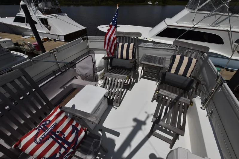  Yacht Photos Pics 2019 Beneteau Swift Trawler 44 deck with wooden chairs, striped cushions, and American flag.