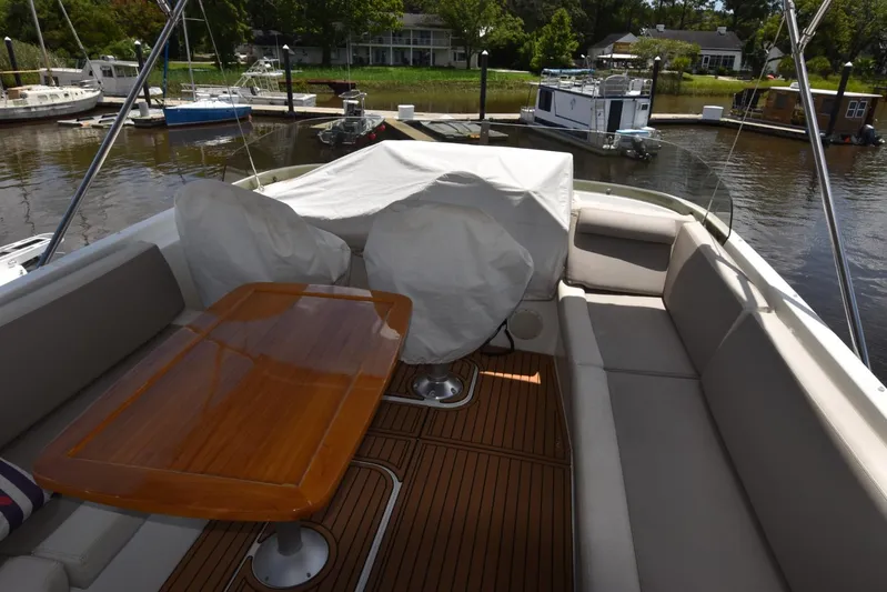  Yacht Photos Pics Flybridge seating area on 2019 Beneteau Swift Trawler 44, featuring a wooden table and covered chairs.