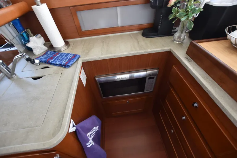  Yacht Photos Pics 2019 Beneteau Swift Trawler 44 kitchen with microwave, sink, and wooden cabinetry.