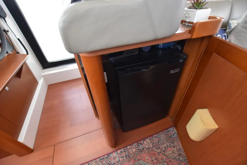  Yacht Photos Pics Interior of 2019 Beneteau Swift Trawler 44 with compact fridge and wooden cabinetry.