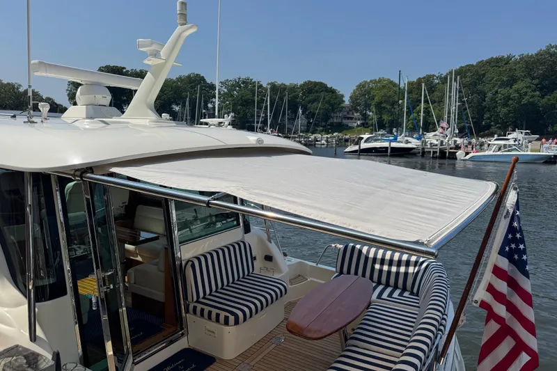 Moving On Yacht Photos Pics 2022 Sabre 48 Salon Express yacht with striped seating and American flag at marina.