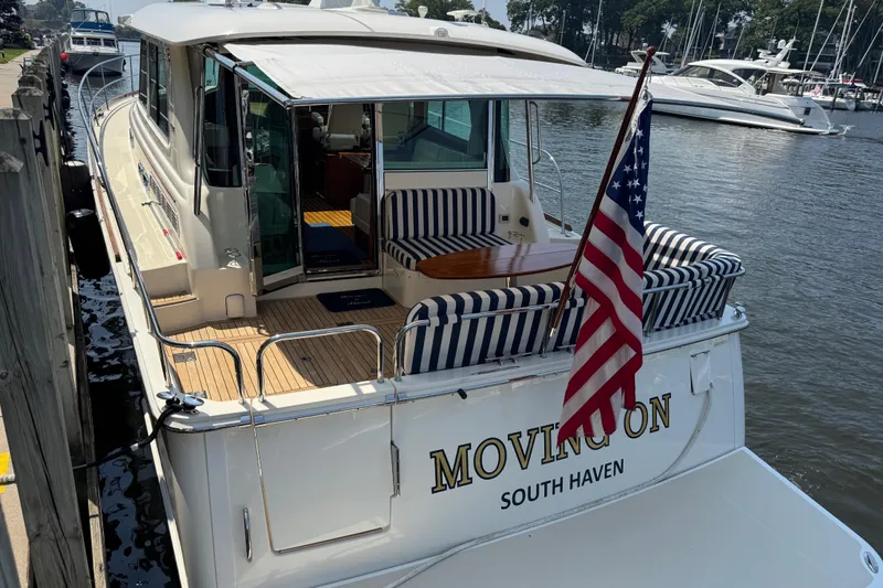 Moving On Yacht Photos Pics 2022 Sabre 48 Salon Express yacht docked, featuring striped seating and American flag.