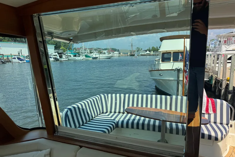 Moving On Yacht Photos Pics Interior view of 2022 Sabre 48 Salon Express yacht with striped seating and marina backdrop.