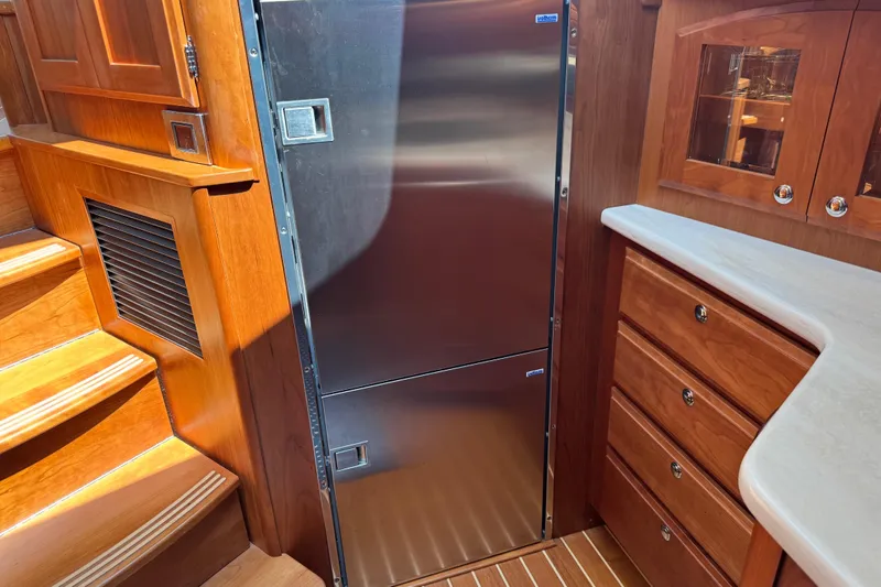 Moving On Yacht Photos Pics Interior of 2022 Sabre 48 Salon Express with stainless steel fridge and wooden cabinetry.
