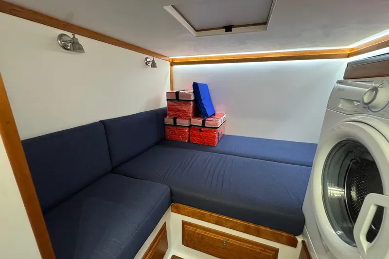 Moving On Yacht Photos Pics Interior of 2022 Sabre 48 Salon Express with blue seating and washing machine.