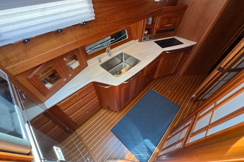 Moving On Yacht Photos Pics 2022 Sabre 48 Salon Express kitchen with wood cabinetry, sink, and stovetop.