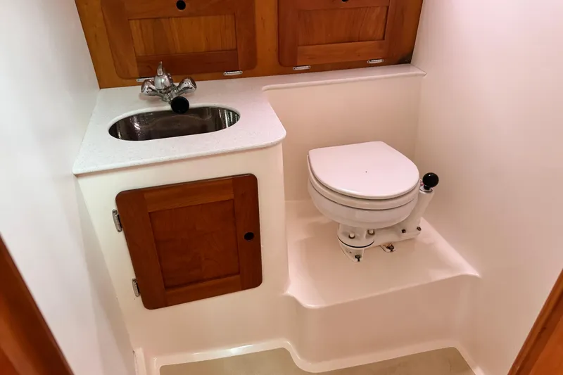 Pastis Yacht Photos Pics Compact boat bathroom with sink, toilet, and wooden cabinetry in a 2005 Hunt SurfHunter.