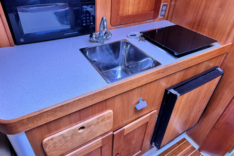 Pastis Yacht Photos Pics Compact kitchen area in a 2005 Hunt SurfHunter boat with sink, microwave, and stove.