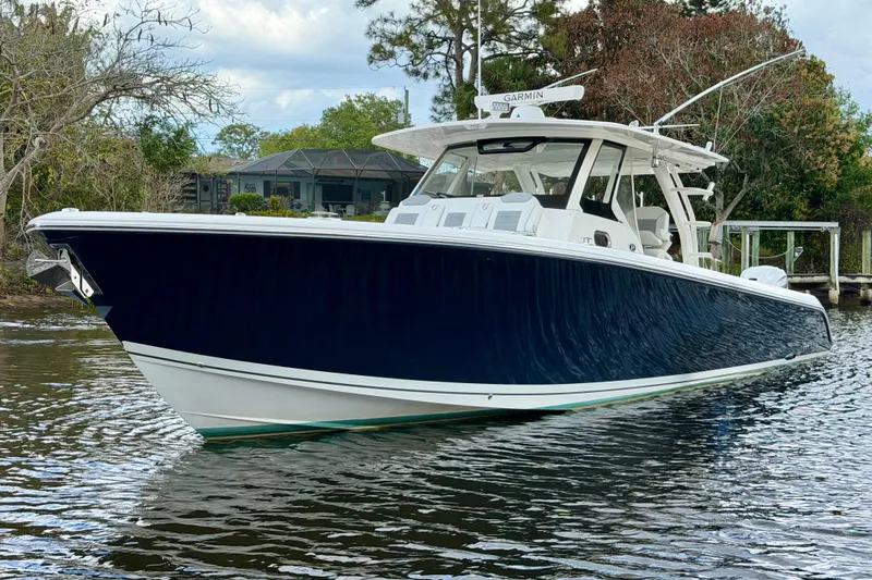 Seakeeper Yacht Photos Pics 2020 Pursuit S 408 Sport boat on calm water, surrounded by trees.
