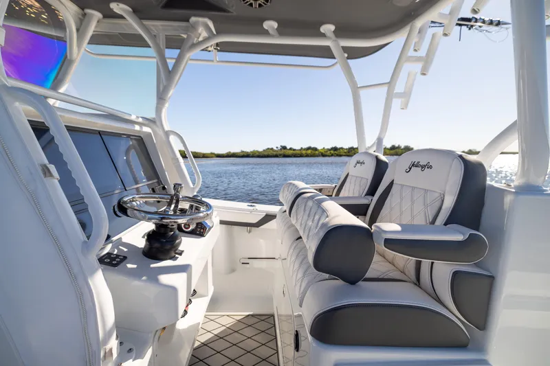Bid Time 2 Yacht Photos Pics 2023 Yellowfin 36 Offshore boat interior with luxurious seating and steering wheel, overlooking serene water.