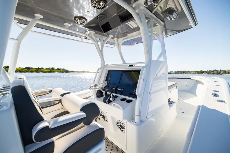 Bid Time 2 Yacht Photos Pics 2023 Yellowfin 36 Offshore boat interior with modern helm and seating, cruising on a sunny day.