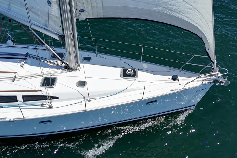  Yacht Photos Pics Jeanneau Sun Odyssey 43 sailboat from 2002 gliding on the water with sails unfurled.