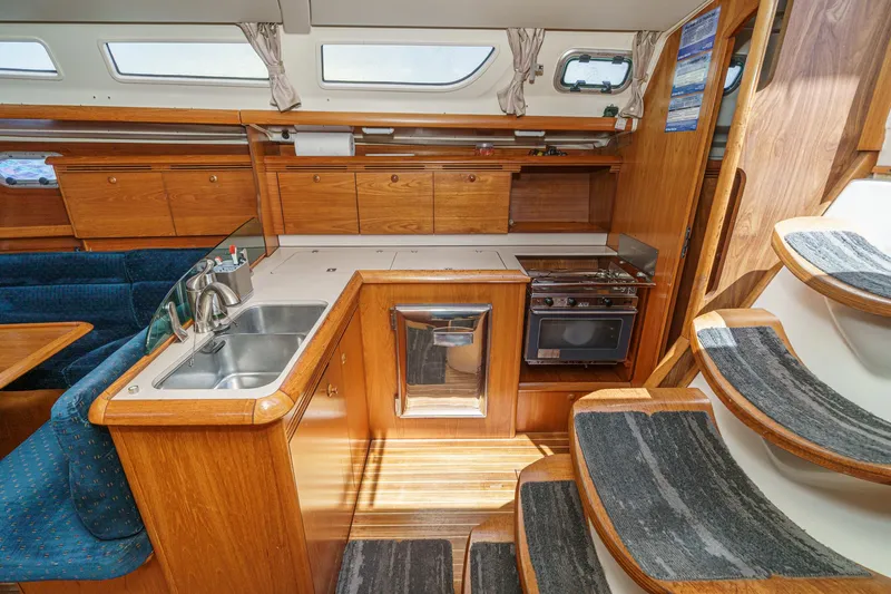  Yacht Photos Pics Interior of 2002 Jeanneau Sun Odyssey 43 yacht, featuring kitchen and wooden cabinetry.