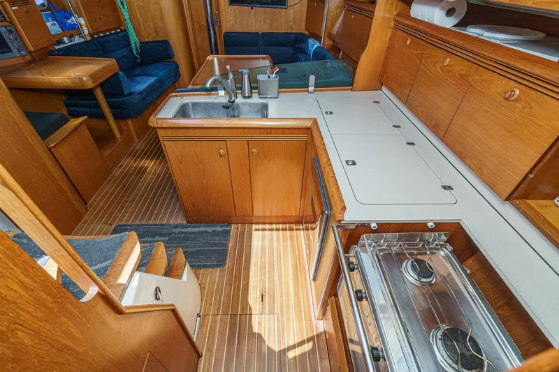  Yacht Photos Pics Interior of 2002 Jeanneau Sun Odyssey 43 yacht, featuring a wooden kitchen and seating area.
