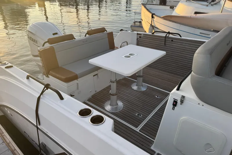 Spritz Yacht Photos Pics 2022 Beneteau Flyer 9 SPACEdeck boat interior with seating and table, docked at sunset.
