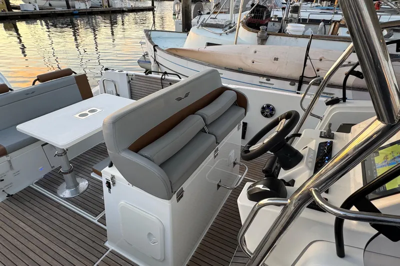 Spritz Yacht Photos Pics 2022 Beneteau Flyer 9 SPACEdeck interior with helm, seating, and table in marina setting.