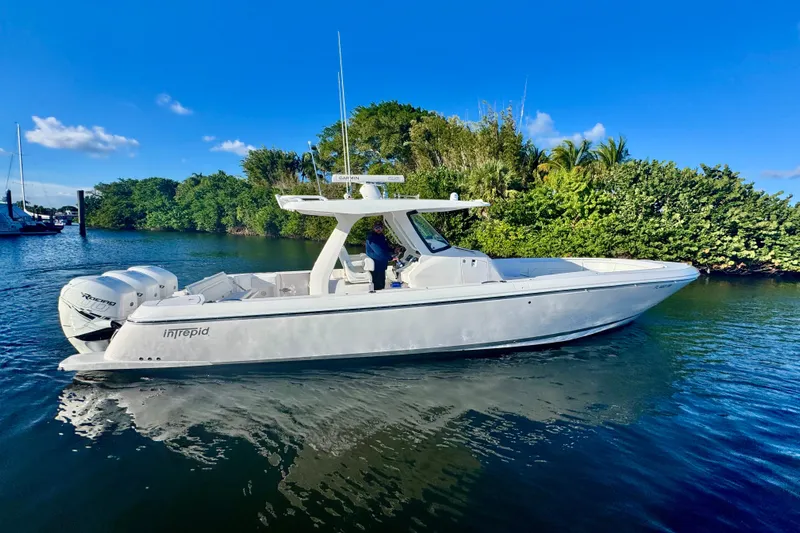  Yacht Photos Pics 2020 Intrepid 375 Nomad SE boat on calm water, surrounded by lush greenery.
