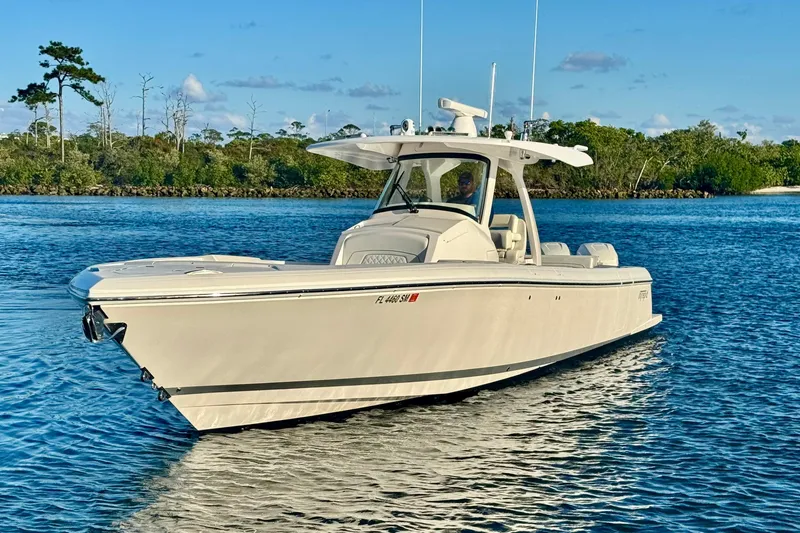  Yacht Photos Pics 2020 Intrepid 375 Nomad SE boat on calm water, surrounded by lush greenery.