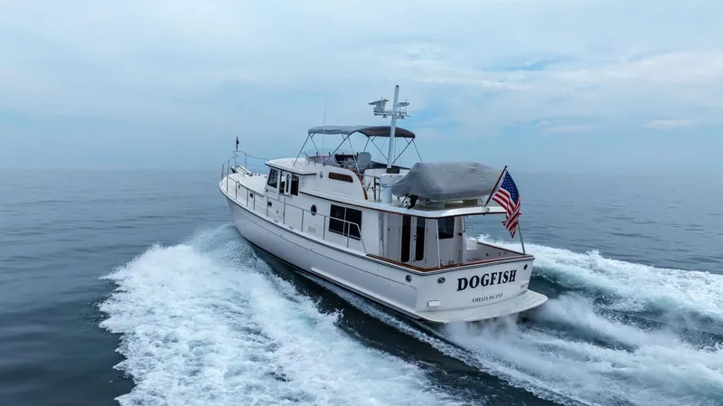 Dogfish Yacht Photos Pics 2023 Krogen Express 52 yacht cruising on open water, American flag displayed.