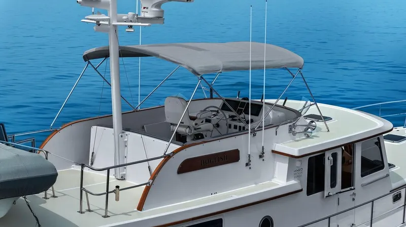 Dogfish Yacht Photos Pics 2023 Krogen Express 52 yacht with canopy, cruising on calm blue waters.