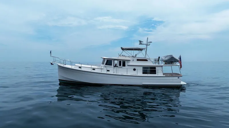 Dogfish Yacht Photos Pics 2023 Krogen Express 52 yacht on calm ocean waters under a cloudy sky.