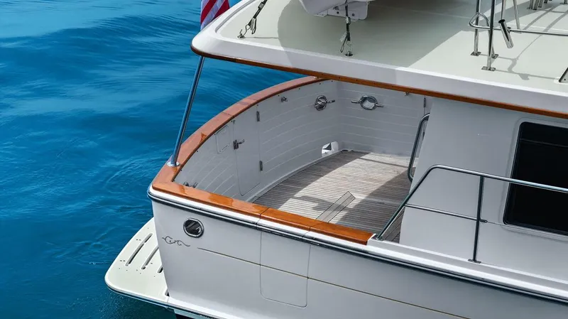 Dogfish Yacht Photos Pics 2023 Krogen Express 52 yacht stern with teak deck and railing on blue water.